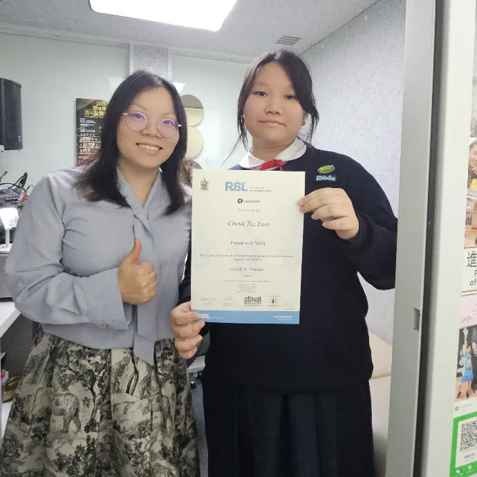 香港敢唱音樂學院學生成功見證：中學生 Karena 在 Miss Ho 一對一聲樂指導下，僅用 8 個月速成考獲 Rockschool 聲樂 8 級 (Merit) 優異成績證書合照。
