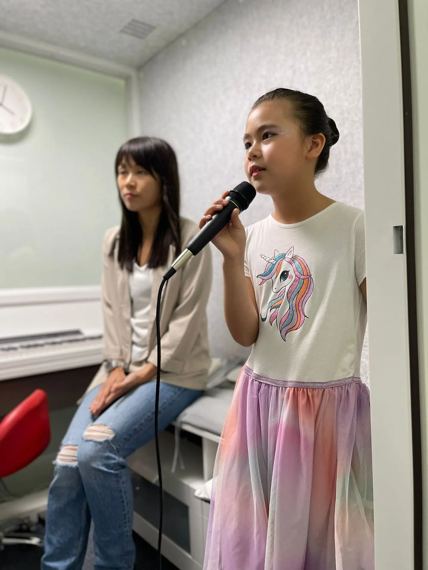 DareToSing Academy 香港兒童唱歌課 小女孩拿麥克風練習演唱 何老師鋼琴旁指導